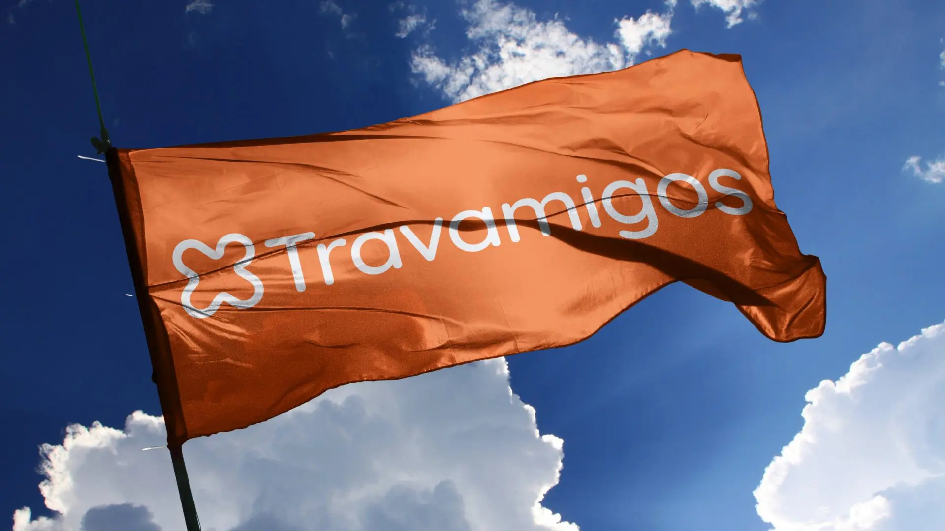 An orange flag with the Travamigos logo against a blue sky