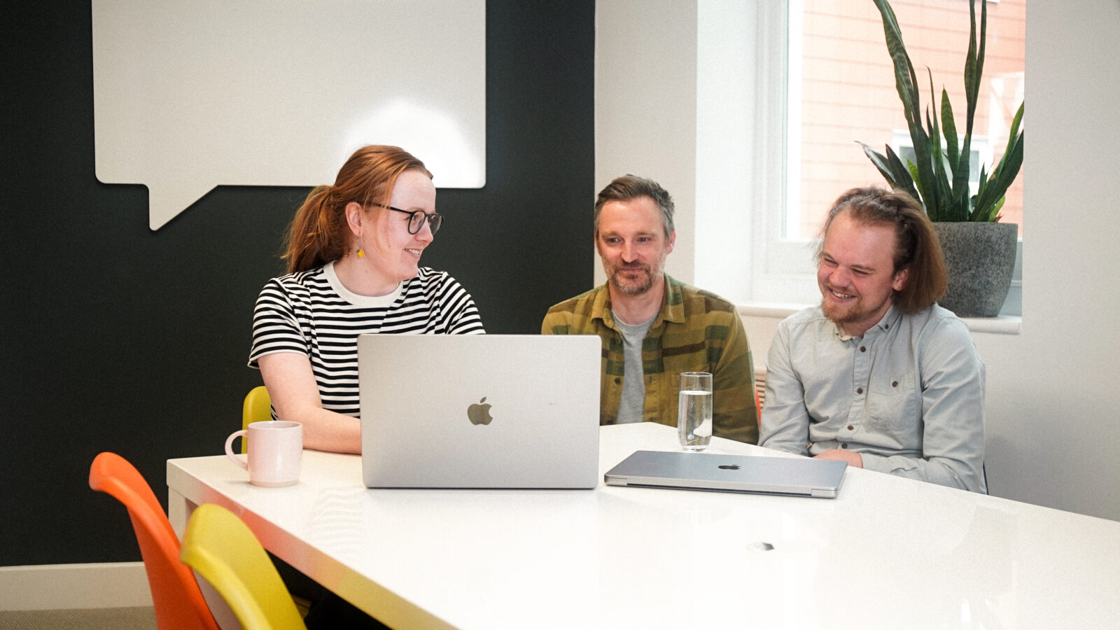Designer, Charly, Designer Designer, Gav and Account Manager, Josh, reviewing work in the meeting room