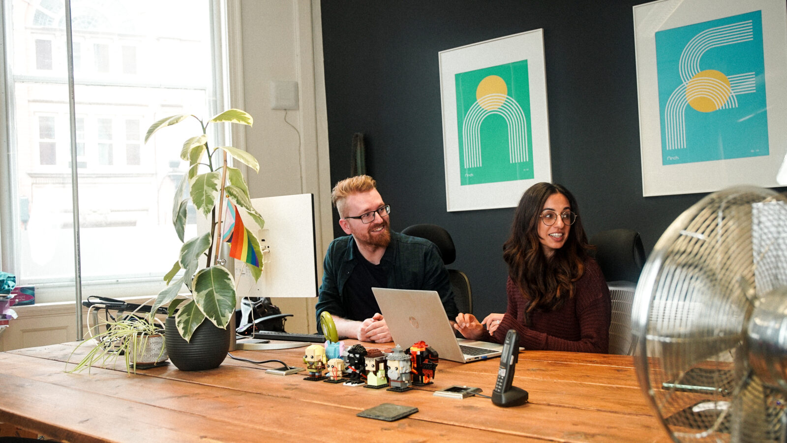 Developer, Matt, and Account Manager, Sarinda, chatting at Matt's desk in the studio